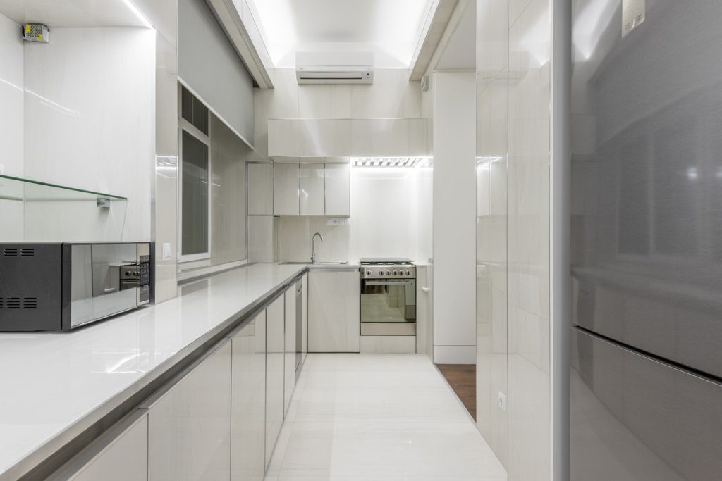 Kitchen in White Tiled Walls and Floor with White Kitchen Cabinets